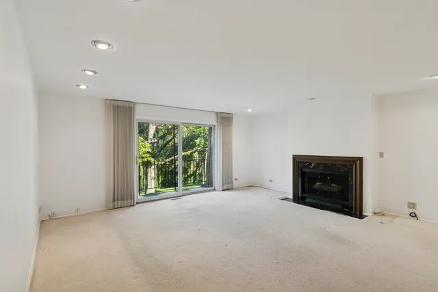 a view of an empty room with a window and fireplace
