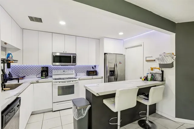 a kitchen with stainless steel appliances a stove a sink a microwave a refrigerator and cabinets