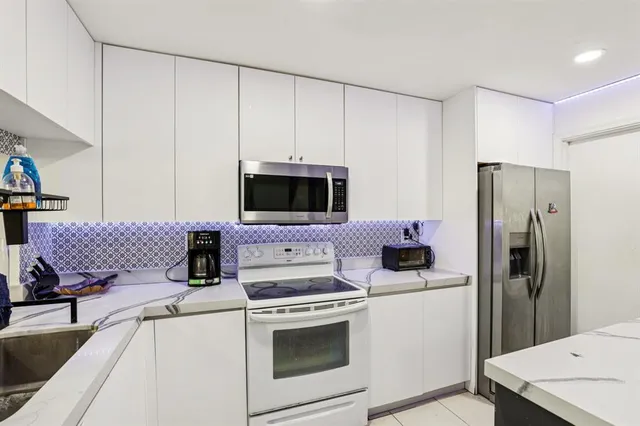 a kitchen with stainless steel appliances white cabinets and a stove top oven