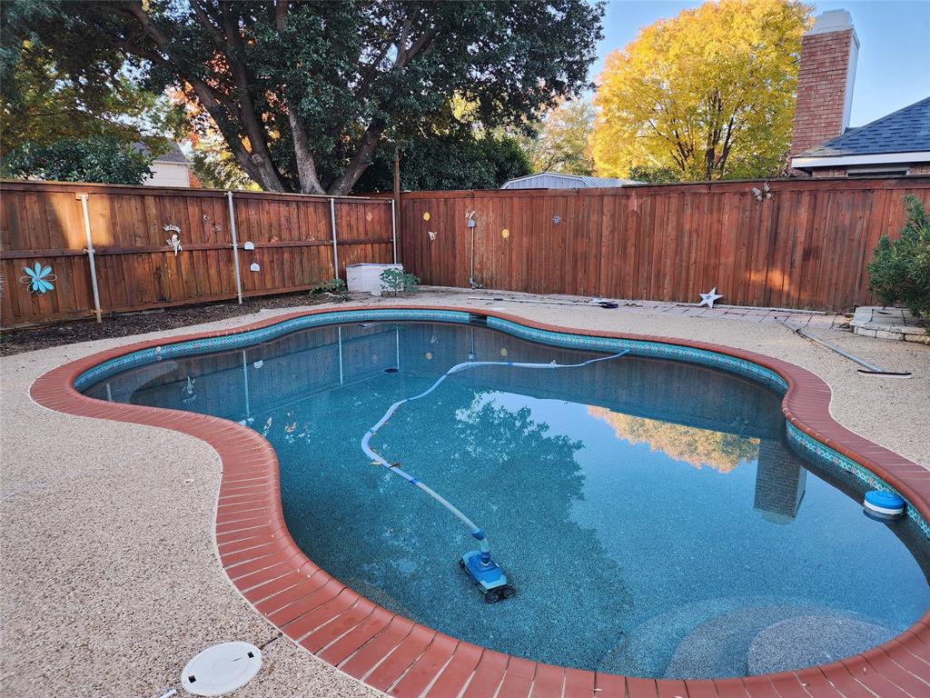 2413 Timber Ridge Lane Flower Mound, TX 75028 - Photo 32 of 32 Freeform swimming pool with a brick coping, aggregate deck, and surrounding privacy fencing