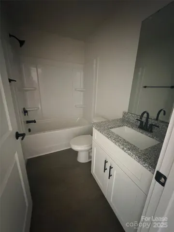 a bathroom with a granite countertop sink a toilet and a tub