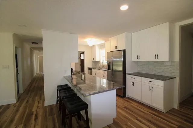 a kitchen with stainless steel appliances granite countertop a sink refrigerator and cabinets