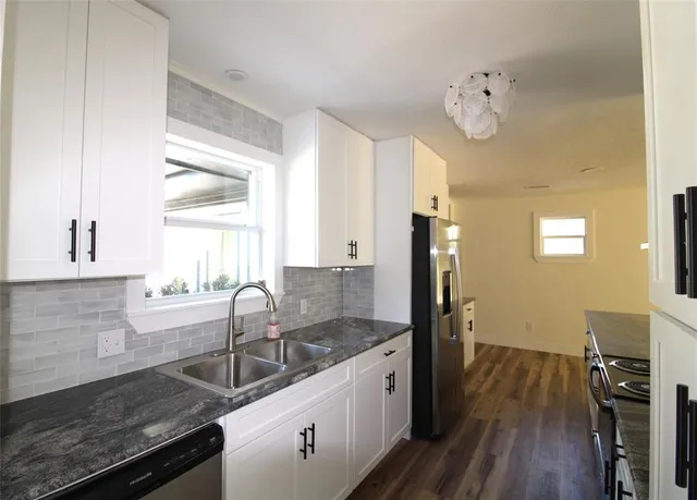 a kitchen with granite countertop a sink appliances cabinets and wooden floor