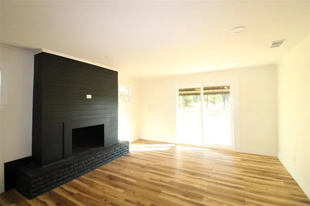 a view of empty room with wooden floor and fireplace