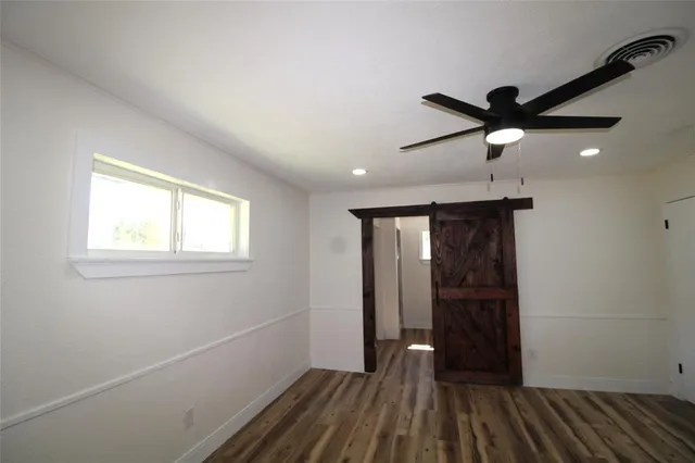a view of an empty room with a window and wooden floor
