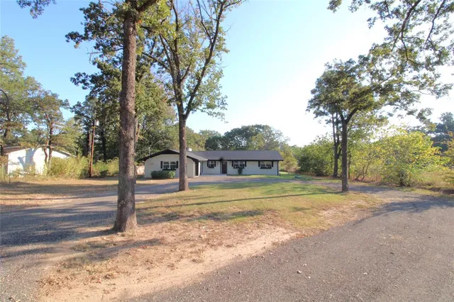 a view of a house with a big yard and large trees
