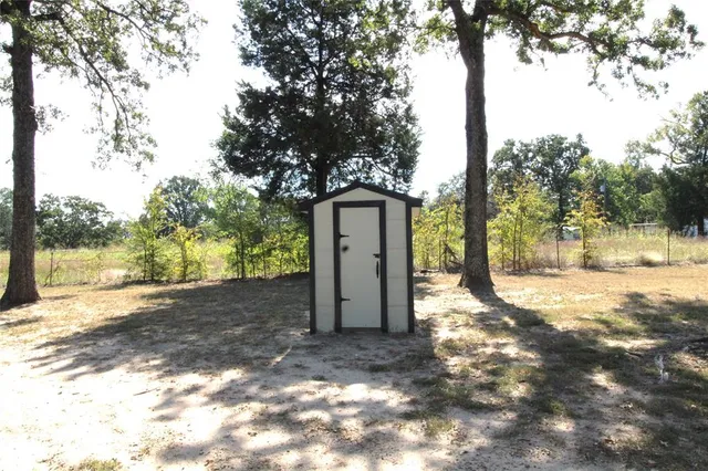 a backyard of a house with a tree and wooden fence