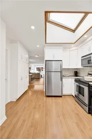 a kitchen with stainless steel appliances a refrigerator sink and white cabinets