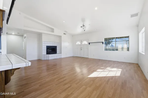 an empty room with wooden floor fireplace and windows