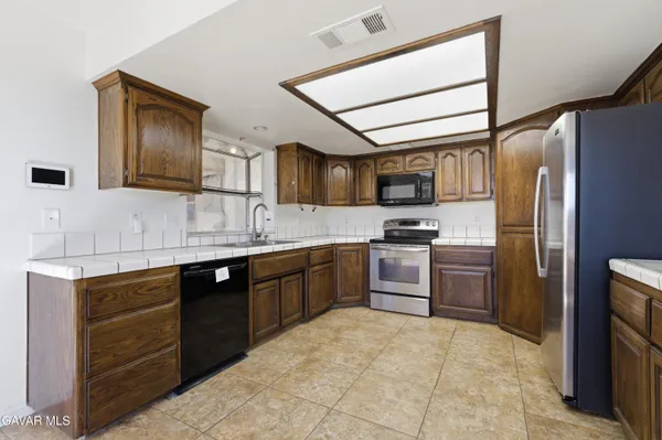 a kitchen with granite countertop a refrigerator stove top oven and sink