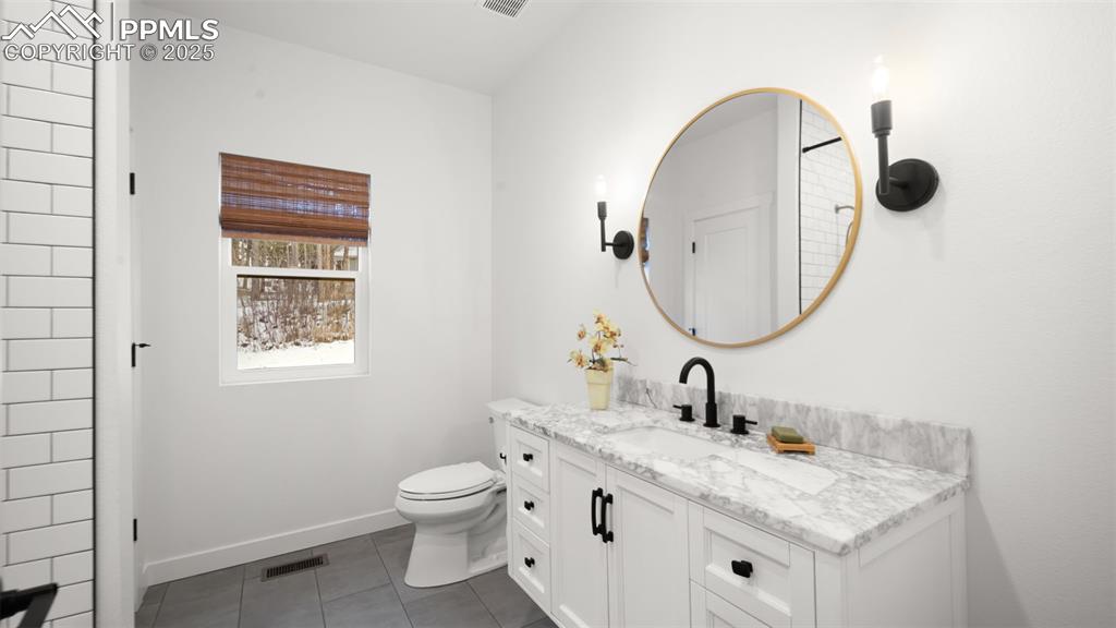 13455 Ravine Drive West Colorado Springs, CO 80908 - Photo 18 of 32 a bathroom with a granite countertop toilet a sink and a mirror