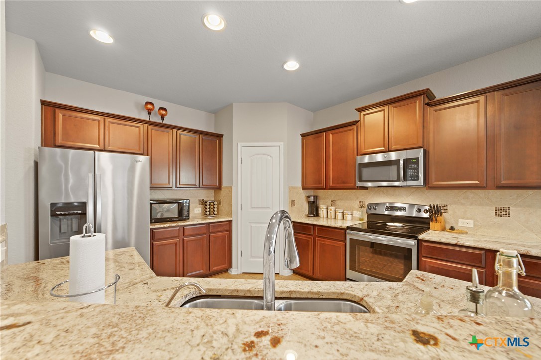 232 Albarella Cibolo, TX 78108 - Photo 13 of 42 a kitchen with stainless steel appliances granite countertop a stove top oven a sink a dining table and chairs