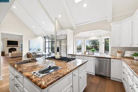 a kitchen with stainless steel appliances granite countertop a stove a sink and white cabinets