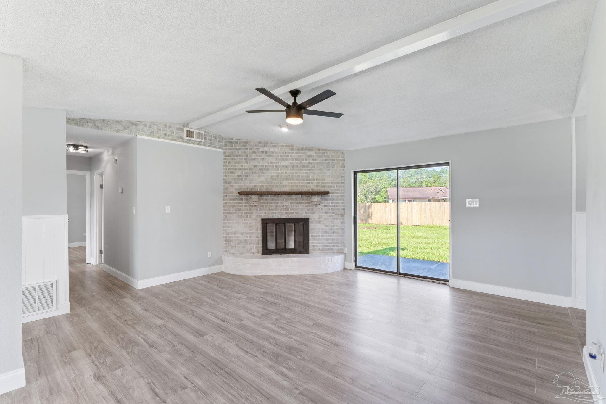 2501 Argle Road Cantonment, FL 32533 - Photo 11 of 36 an empty room with wooden floor a ceiling fan and a fireplace