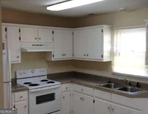 a kitchen with granite countertop white cabinets and white stove