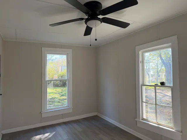 an empty room with windows and ceiling fan