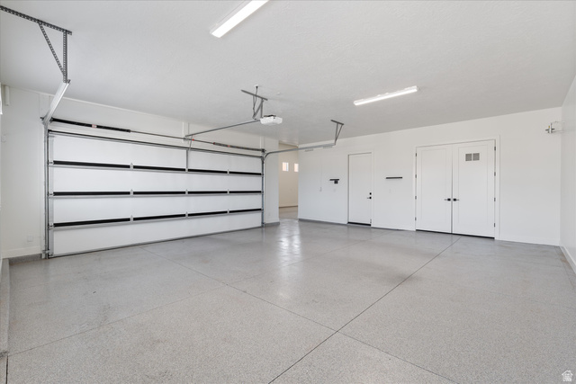 1192 East Corral Way Washington, UT 84780 - Photo 68 of 81 Spacious garage featuring an epoxy-coated concrete floor, white walls, and a large overhead door with an automatic opener