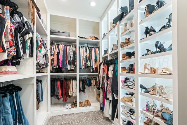 a view of walk in closet with clothes and shoes
