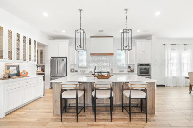 a kitchen with stainless steel appliances kitchen island granite countertop a table chairs and a refrigerator