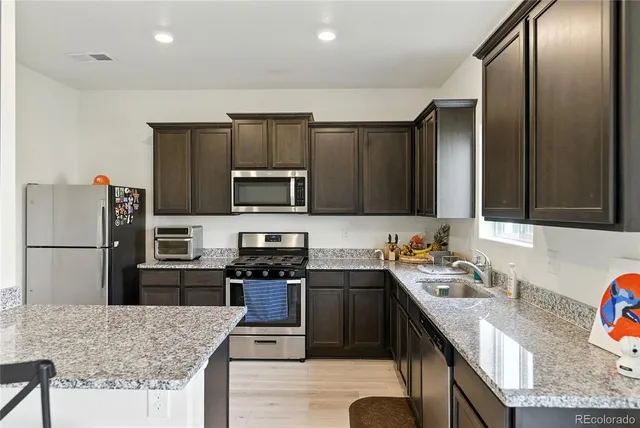 a kitchen with stainless steel appliances granite countertop a sink refrigerator and microwave