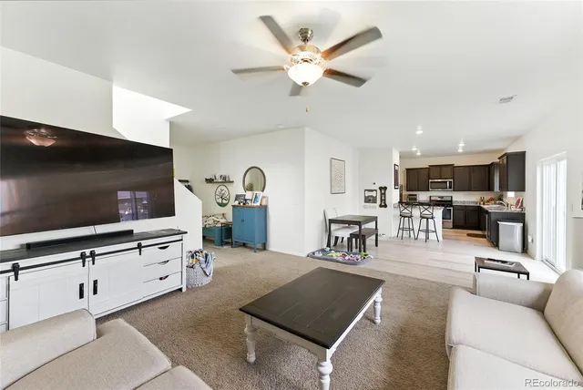 a living room with furniture a table and kitchen view