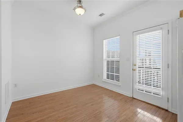an empty room with wooden floor and windows