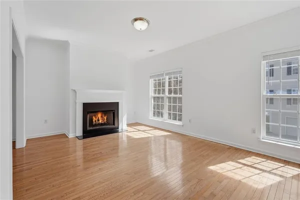 an empty room with wooden floor fireplace and windows