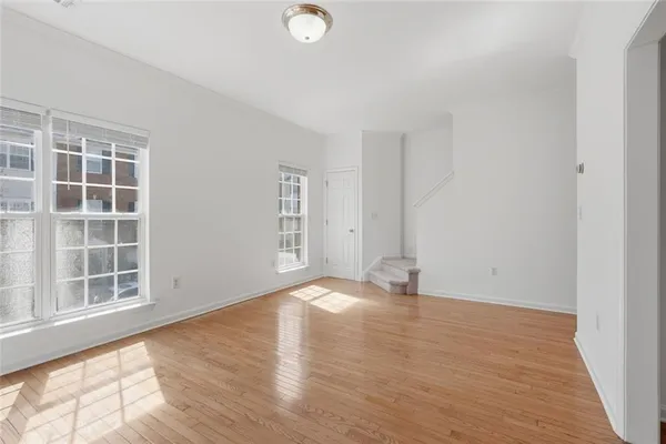 an empty room with wooden floor and windows