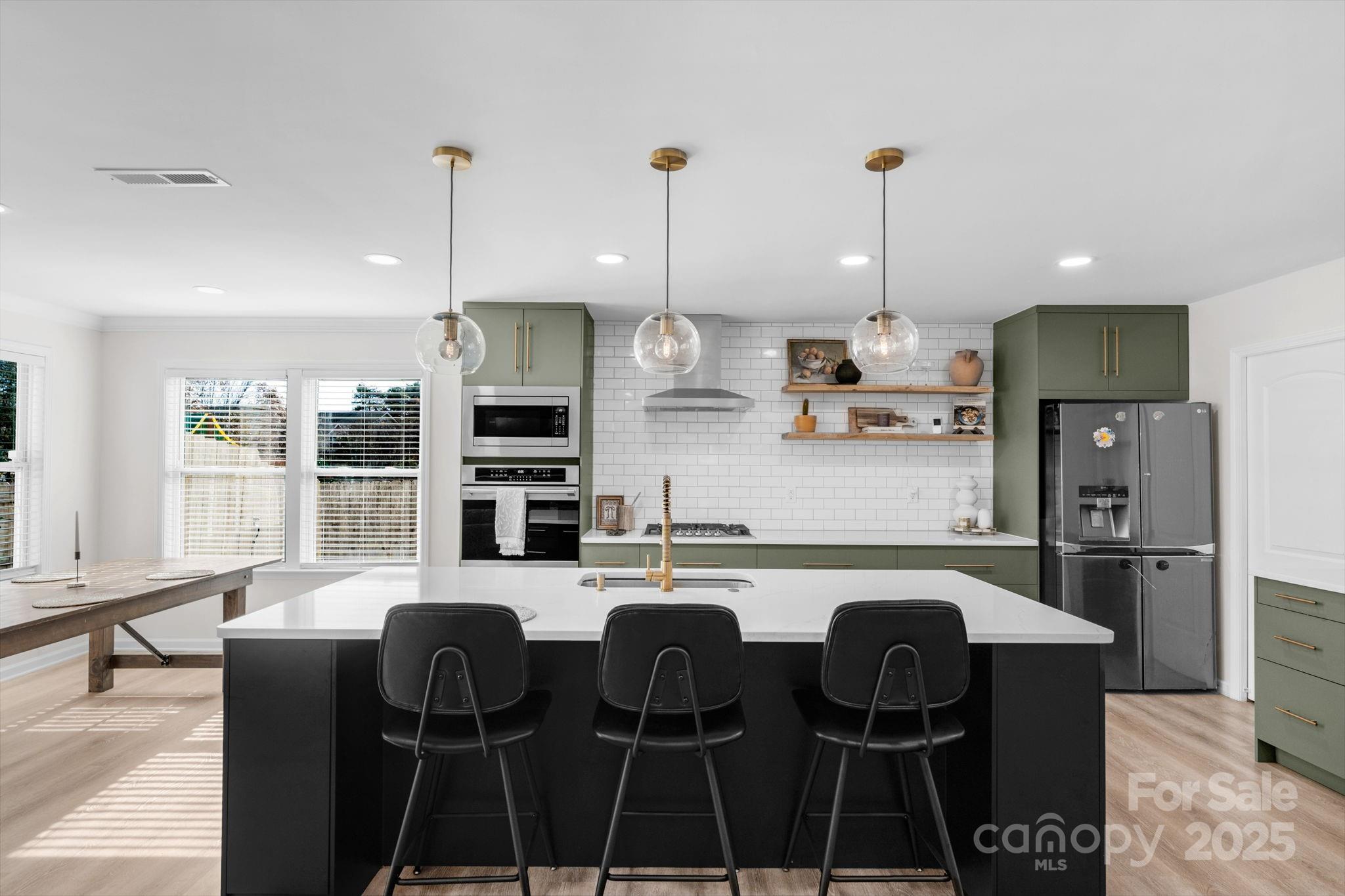 12847 Connemara Court Midland, NC 28107 - Photo 17 of 47 a kitchen with stainless steel appliances granite countertop a stove a sink a refrigerator a dining table and chairs with wooden floor