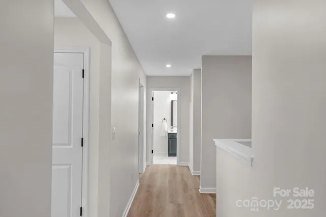 a view of a hallway with wooden floor and a bathroom