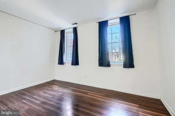 a view of an empty room with wooden floor and closet