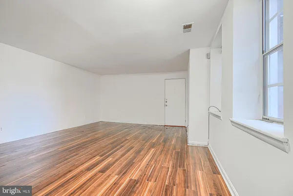 a view of a room with wooden floor and a ceiling fan