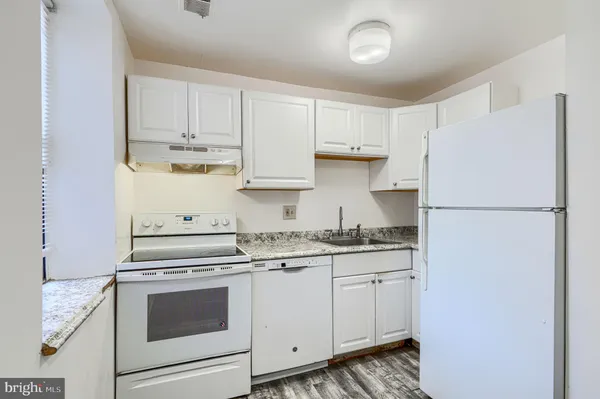 a kitchen with granite countertop white cabinets and white appliances