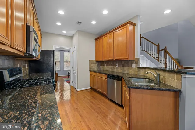 a kitchen with granite countertop kitchen island stainless steel appliances a stove a sink and a microwave