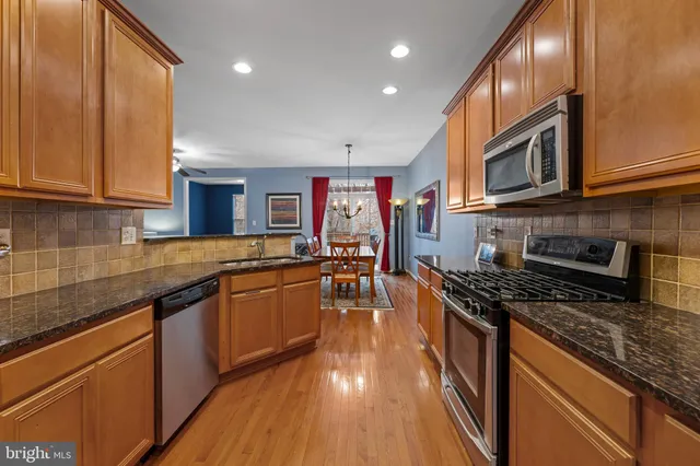 a kitchen with stainless steel appliances granite countertop a stove top oven a sink dishwasher and cabinets with wooden floor