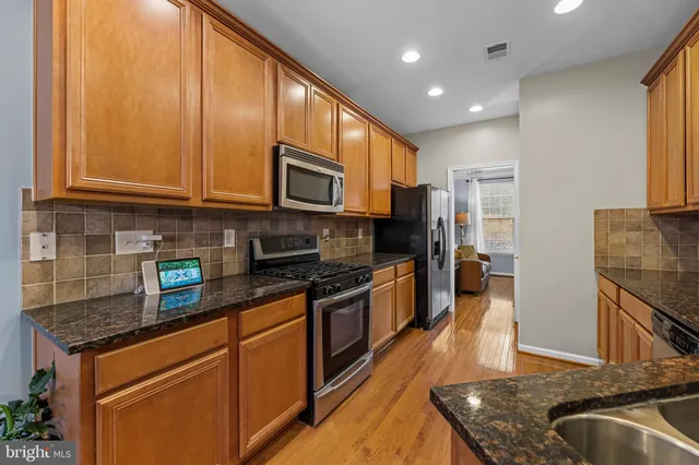 a kitchen with stainless steel appliances granite countertop a stove a sink and a microwave
