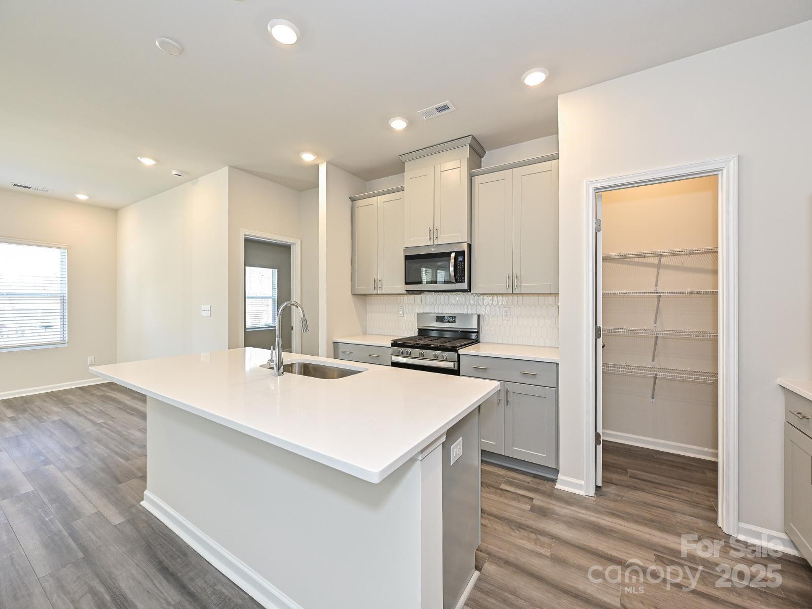 178 Nelson Crk Road Mocksville, NC 27028 - Photo 5 of 7 a kitchen with a sink a stove a refrigerator and white cabinets with wooden floor