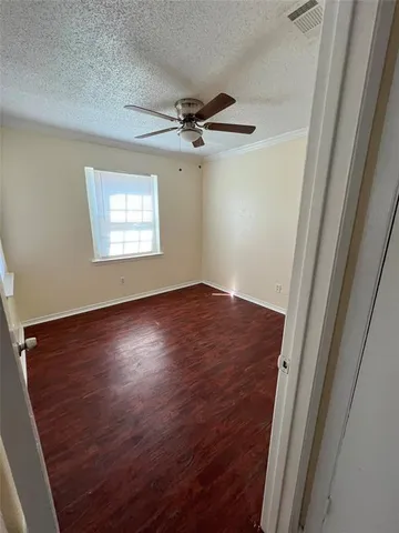an empty room with wooden floor fan and windows