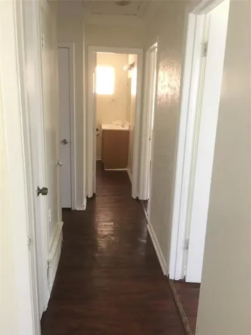 a view of a hallway with wooden floor and a bathroom
