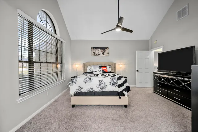 a bedroom with a bed and a flat tv screen on the dresser