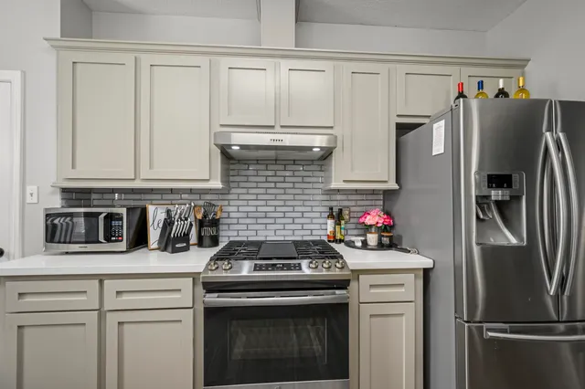 a kitchen with stainless steel appliances white cabinets and a refrigerator