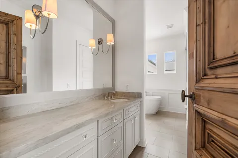 a bathroom with a granite countertop sink a toilet a mirror and shower