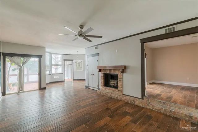 an empty room with wooden floor fireplace and windows