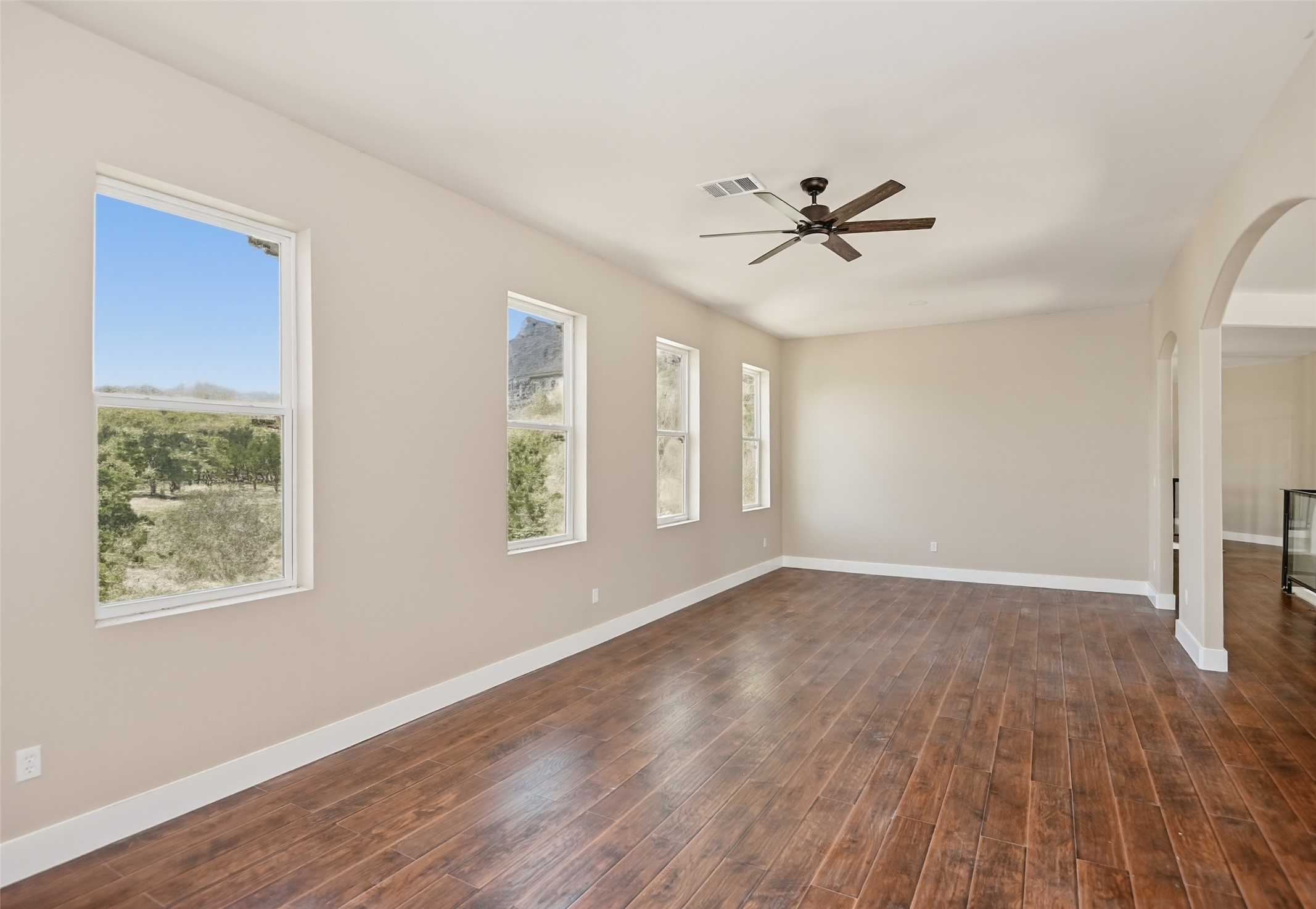 14300 Fallen Timber Drive Austin, TX 78734 - Photo 29 of 35 an empty room with wooden floor ceiling fan and windows