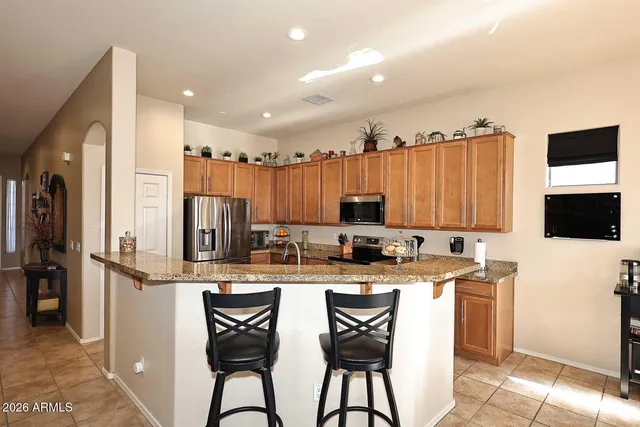 a kitchen with stainless steel appliances a sink a stove a refrigerator cabinets and a dining table with wooden floor