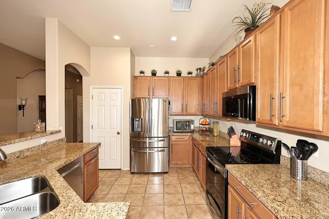 a kitchen with stainless steel appliances granite countertop a refrigerator a stove and a sink with wooden floor