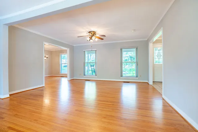 an empty room with wooden floor and windows