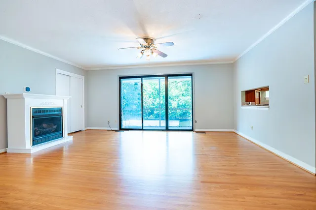 a view of an empty room with window wooden floor and fire place