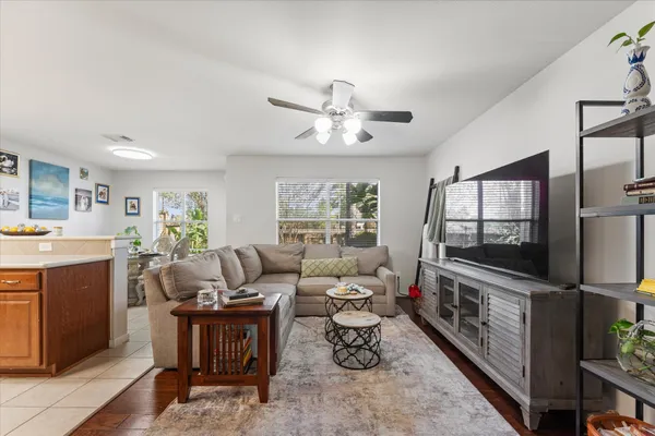 a living room with furniture a flat screen tv and a refrigerator