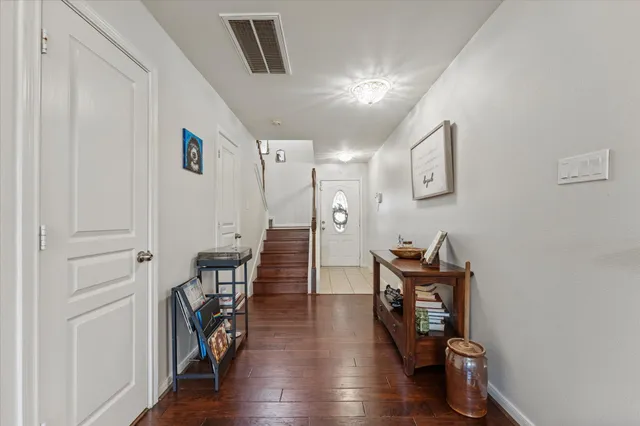 a hallway with wooden floor a dining table and chairs